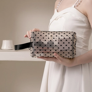 Black heart pattern mesh makeup bag with handle held by model in casual setting