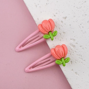 Detail shot of two pink metal hair clips with cute tulip floral decorations for girls
