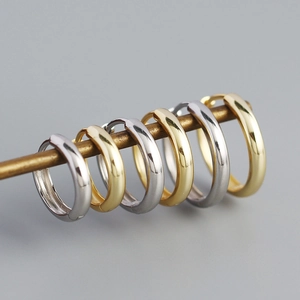 Close-up of minimalist gold and silver polished hoop earrings on a display bar