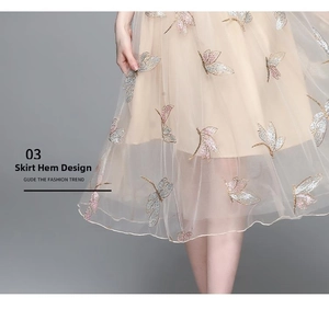 Detailed view of champagne mesh skirt featuring 3D butterfly embroidery and layered fabric
