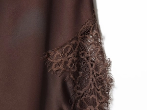 Macro detail of dark brown satin fabric with intricate matching eyelash lace trim