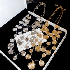 Macro shot of layered gold and silver necklaces with hammered metal coin pendants