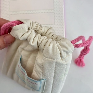 Detail of quilted drawstring makeup pouch with pink cotton rope and studio label