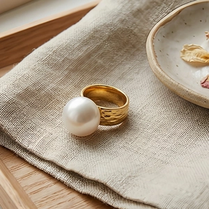 Detailed view of large white pearl on golden hammered texture stainless steel ring