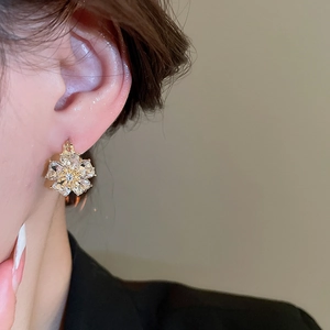 Close-up of double-sided diamond flower stud earrings with cat-eye stone on a model ear
