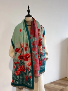Detail eines rot-grünen Schals mit Blumenmuster und eleganten Quastenkanten an einer Puppe