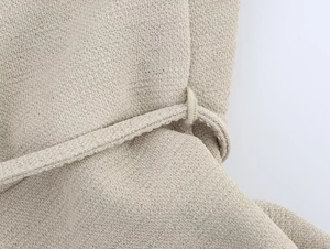 Dettaglio vita abito in maglia con passanti e trama di tessuto beige a costine