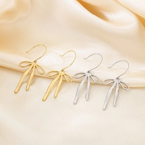 Elegant gold and silver bow drop earrings on silk fabric for a stylish summer look