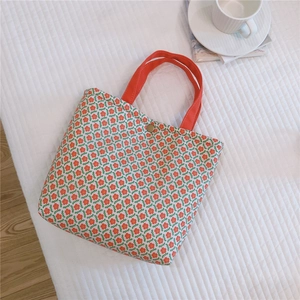 Detailed view of floral canvas tote bag with orange handles and bronze magnetic closure