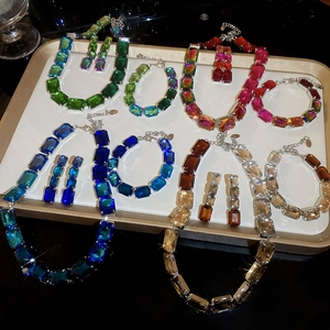 Close-up of radiant square-cut crystal jewelry sets in gradient colors on a tray