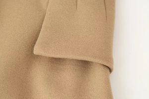 Detailed macro view of camel wool fabric texture and stitching on a notched lapel coat