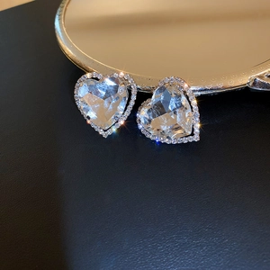Macro shot of silver heart earrings with sparkling large zircon and rhinestone pavé halo