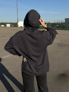 Πίσω όψη από σκούρο γκρι oversized φούτερ με κουκούλα και χαμηλωμένους ώμους