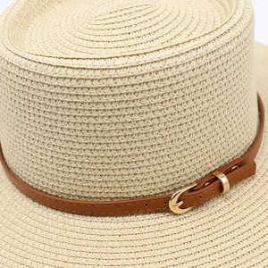 Dettaglio ravvicinato del cappello di paglia beige con trama intrecciata e cinturino
