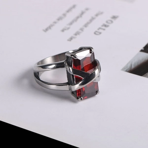Close-up of a silver ring with a large rectangular red gemstone and hollow band detail