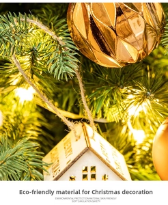Detail of wooden Merry Christmas house ornament and golden ball on LED tree