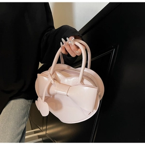Gros plan du sac à main rose en forme de cœur avec un grand nœud et une finition laquée