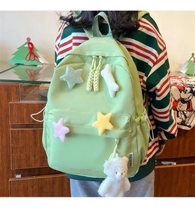 Detail of light green canvas backpack with plush stars and cute white bear keychain