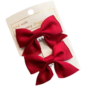 Pair of handmade red bow hair clips for kids on a white card display set
