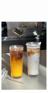 Close-up of fluted glass coffee tumblers with glass straws and secure lids