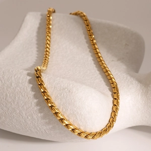 Close-up of golden stainless steel chain necklace on white textured stone display
