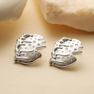 Irregular geometric silver studs with zircon inlays on natural stone background