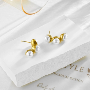 Vintage stainless steel earrings featuring three white pearls on a curved gold base