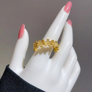 Elegant gold flower ring with zircon stones held in hand, minimalist adjustable band style