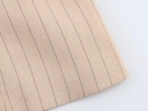 Gros plan sur un tissu tissé beige avec motif à fines rayures noires et texture lisse