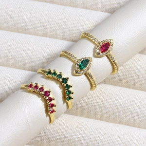 Close-up of four gold rings with emeralds, rubies and small zirconias in a jewelry box