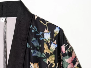 Macro detail of black floral satin blazer with vibrant print and size S neck label