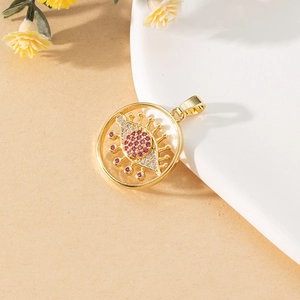 Macro shot of gold Evil Eye pendant with pink crystals on a textured beige background
