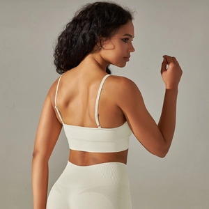 Dettaglio delle spalline incrociate e trama a coste su reggiseno sportivo e leggings crema