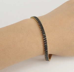 Nahaufnahme eines vergoldeten Edelstahl-Tennisarmbands mit schwarzen Zirkonia am Handgelenk