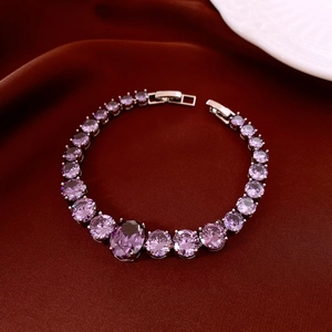 Close-up of a silver zircon bracelet with purple teardrop stones on red velvet
