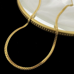 Detailed close-up of a flat gold snake chain necklace with a mirror finish on silk