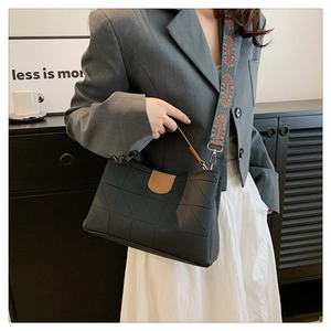 Detail of black quilted shoulder bag with contrast brown buckle and ethnic strap