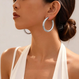 Silver twisted rope texture geometric hoop earrings worn by a female model on a light background