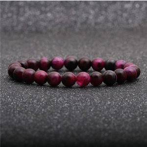 Close-up of pink tiger eye and black beads bracelet on a textured dark background