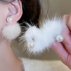 Close-up of fluffy white pom-pom earrings with pearls and soft faux fur texture