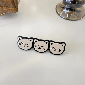 Close-up of three cute white enamel cats hair clip on a white decorative desk