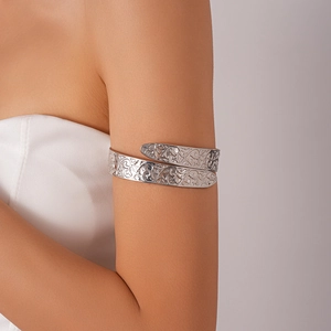 Detail of silver arm cuff featuring intricate floral filigree and hollow-out carving