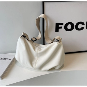 Detail view of the cream crescent tote bag with an adjustable strap and zipper closure