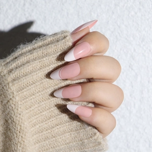 Pink and white French tip mosaic almond press-on nails shown on a cozy sweater background