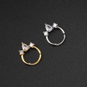 Dettaglio di piercing al naso oro e argento con zirconi scintillanti su sfondo nero opaco
