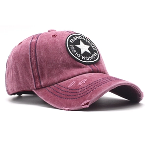 Detail of vintage washed wine red baseball cap with star patch and distressed texture