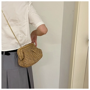 Detail of hand-woven straw shell bag featuring golden chain strap and woven texture