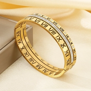 Close-up of golden hollow bangle featuring Roman numerals and sparkling pavé zircons