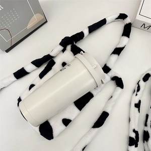 Macro detail of plush cow print water bottle bag with soft faux fur texture and long strap