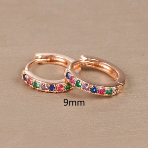 Macro detail of 9mm rose gold huggie earrings with a row of rainbow colored gemstones